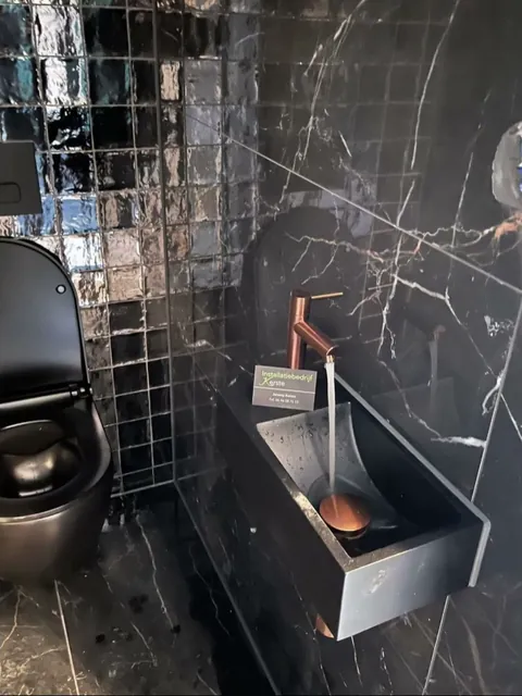 Toilet in zwart marmer met koperen kraan boven een fontein
